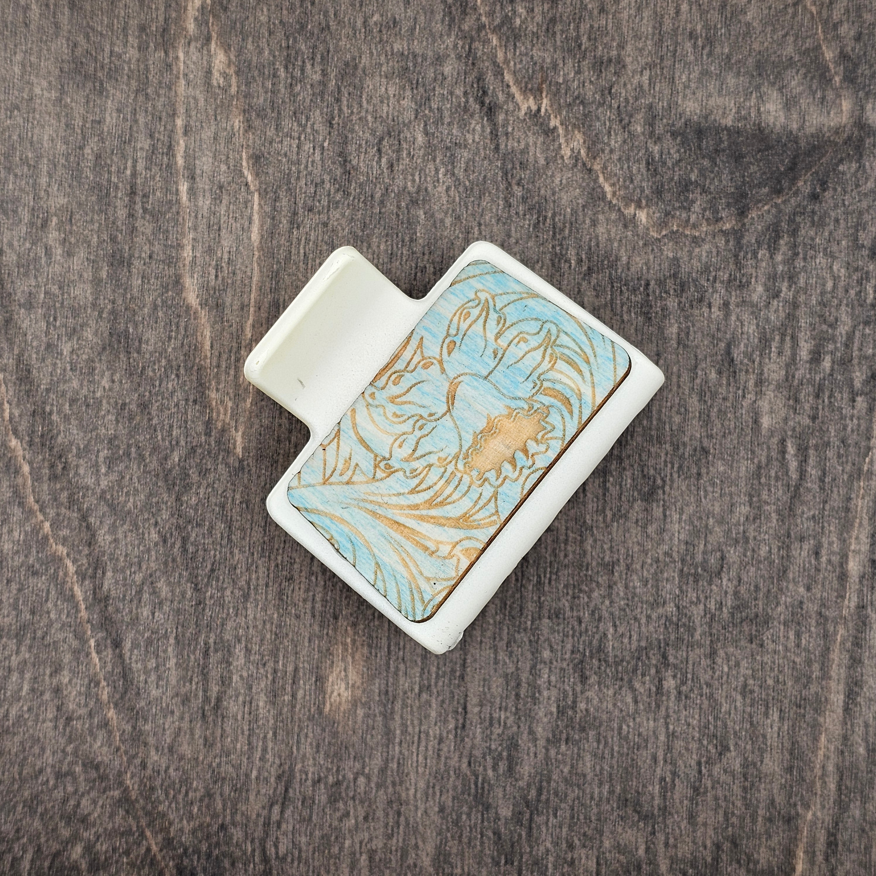 Laser engraved western daffodil on blue-stained wood with natural wood grain revealed through engraving, creating a two-tone aqua and gold effect, set in a 2-inch cream matte claw clip