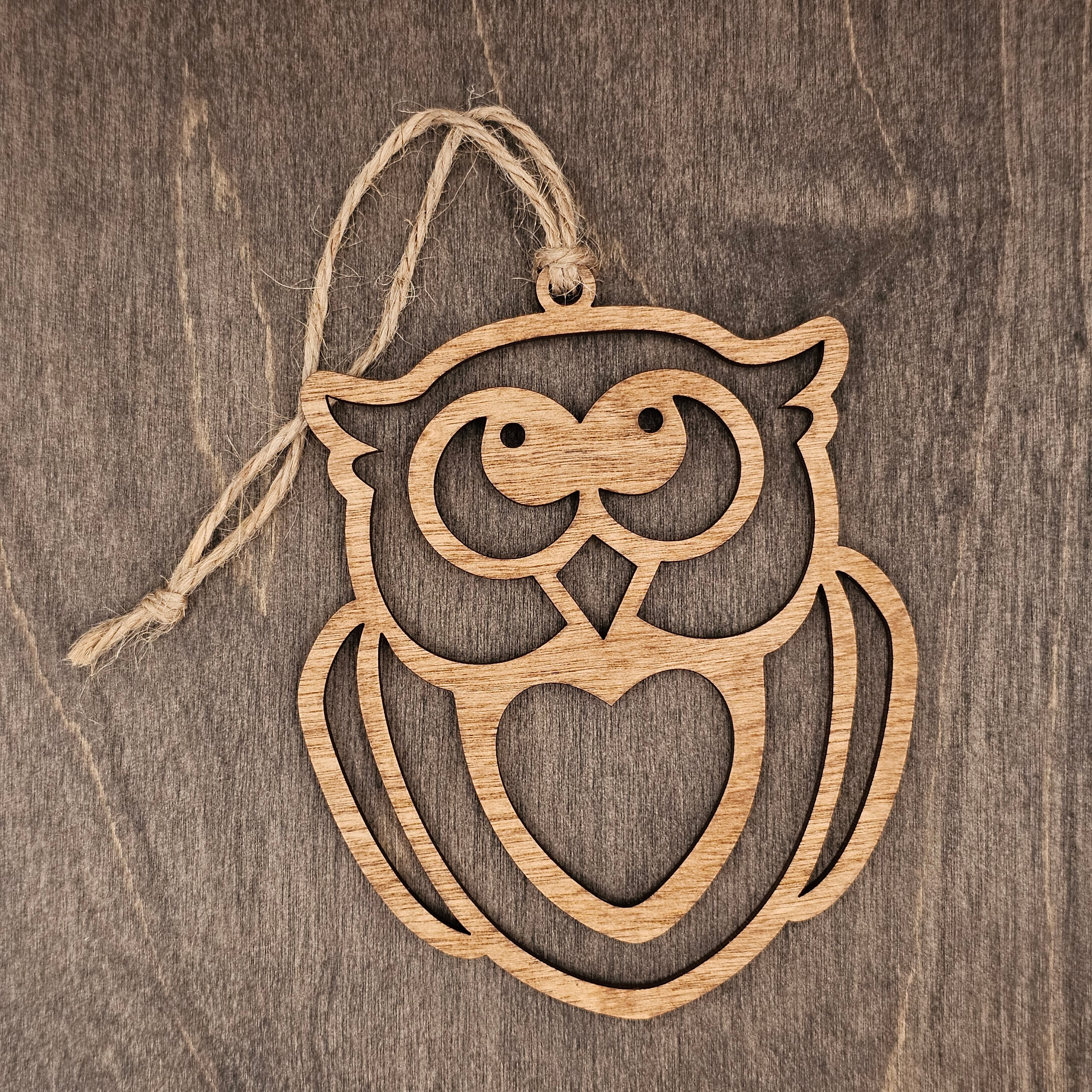 Laser cut owl wood ornament with open heart silhouette design and expressive face, hung with natural jute cord