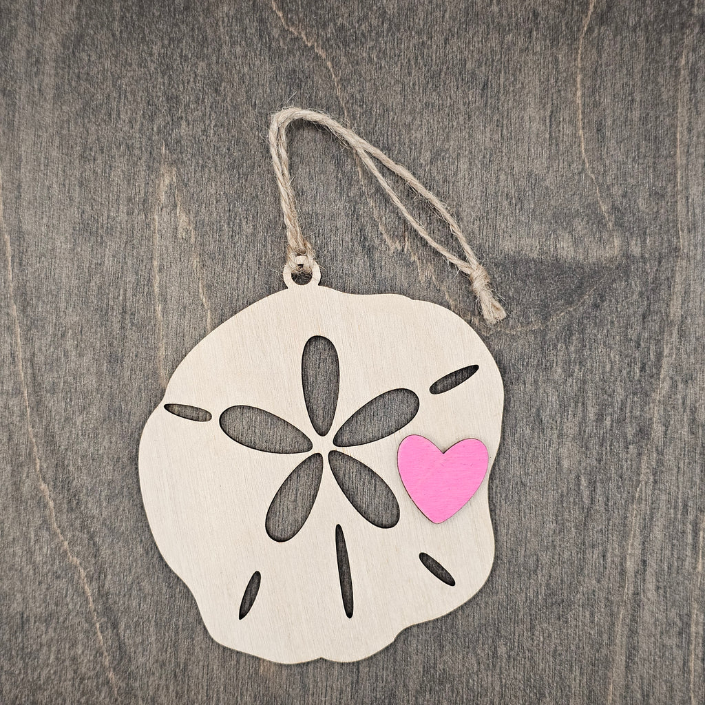 Laser cut wood sand dollar ornament with five-petal cutout and hand-painted pink heart accent, hung with natural jute cord