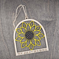Hand-painted laser cut sunflower wood ornament in yellow with dark brown center inside an arched frame, "You Are My Sunshine" engraved at the base, hung with natural jute cord