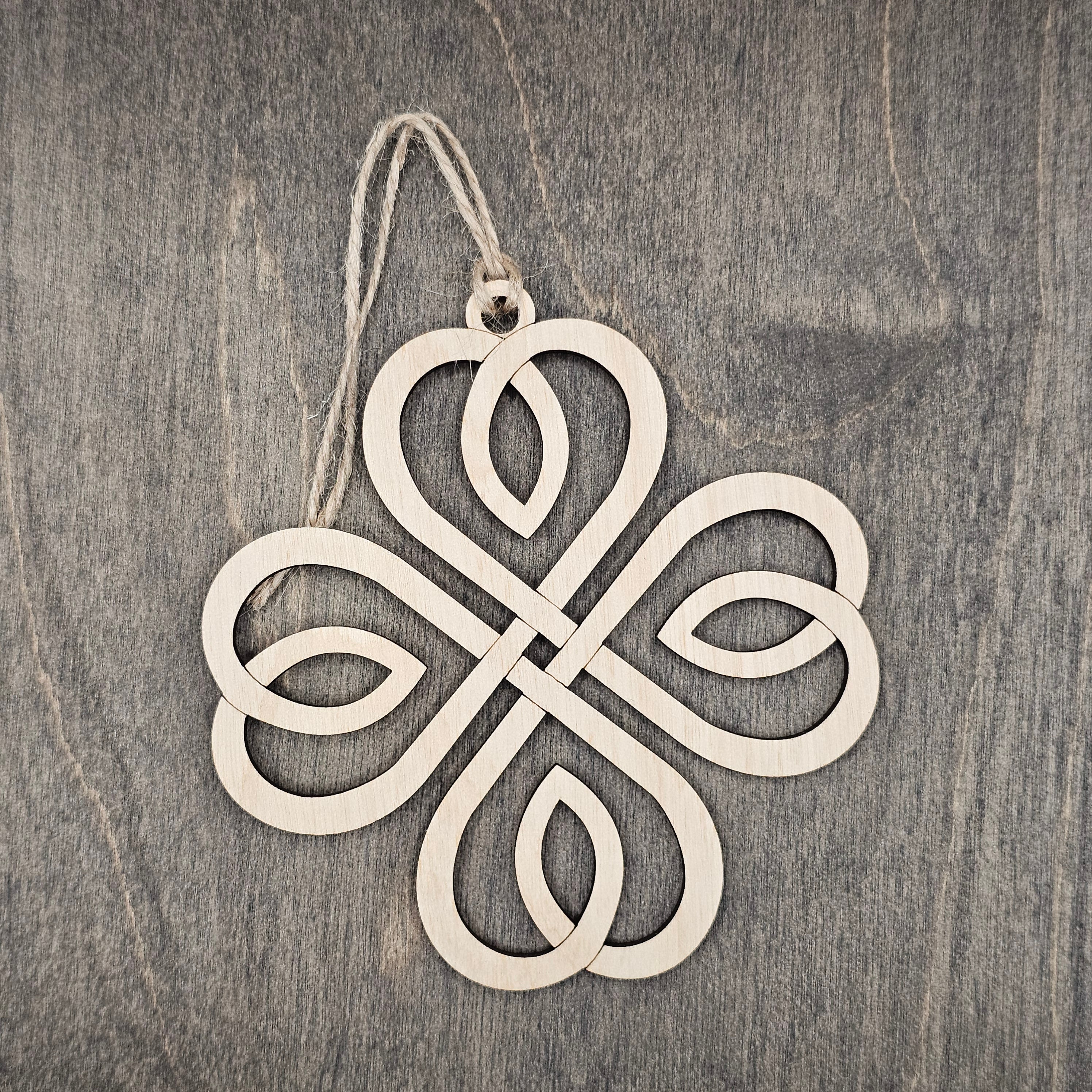 Laser cut Celtic knot wood ornament with intricate open interlace design, hung with natural jute cord