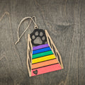 Laser cut Rainbow Bridge cat ornament with hand-painted rainbow colored steps, black cat paw print silhouette, and heart cutout at the base, hung with natural jute cord