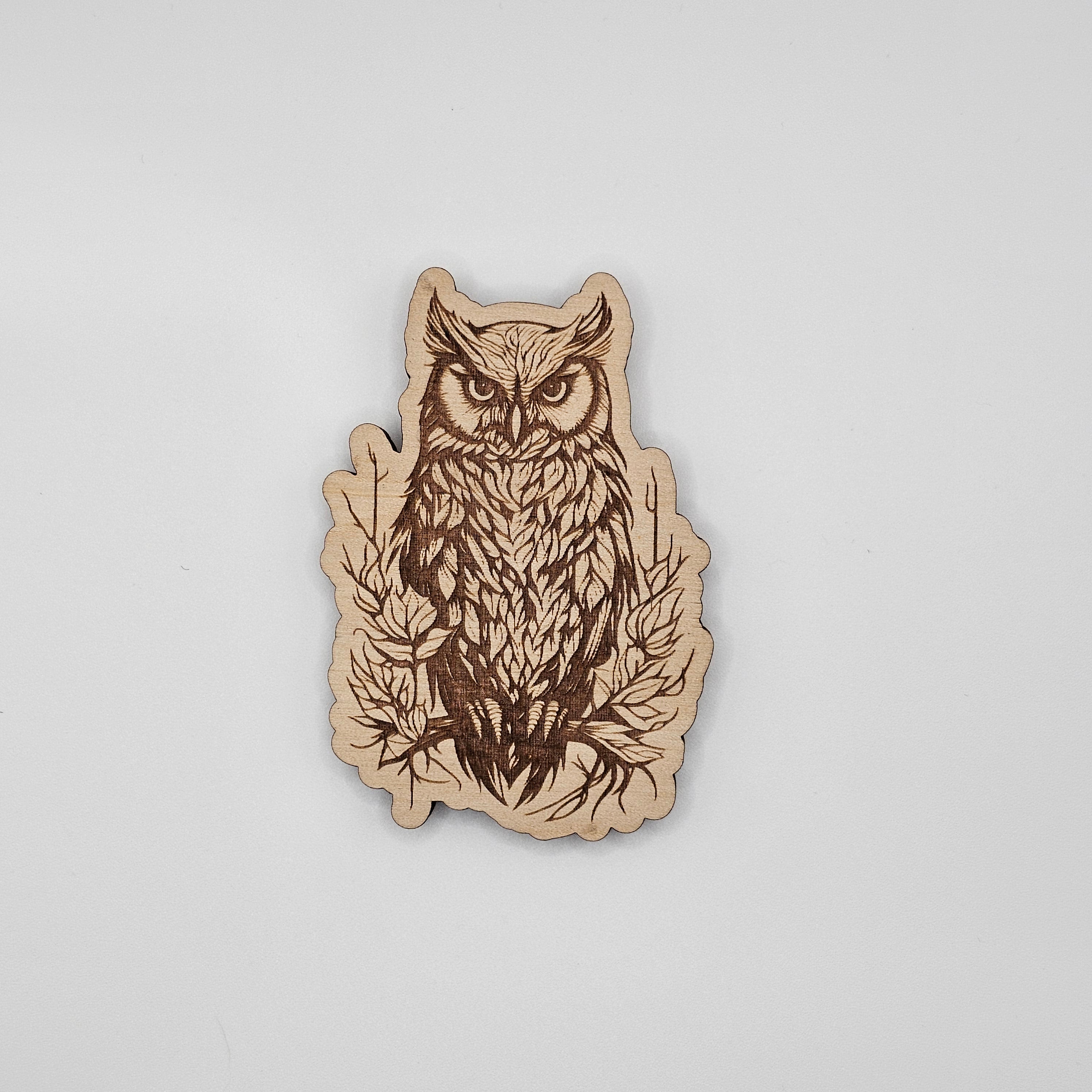 Laser-engraved wood magnet shaped like an owl perched on a branch with detailed feather and leaf design