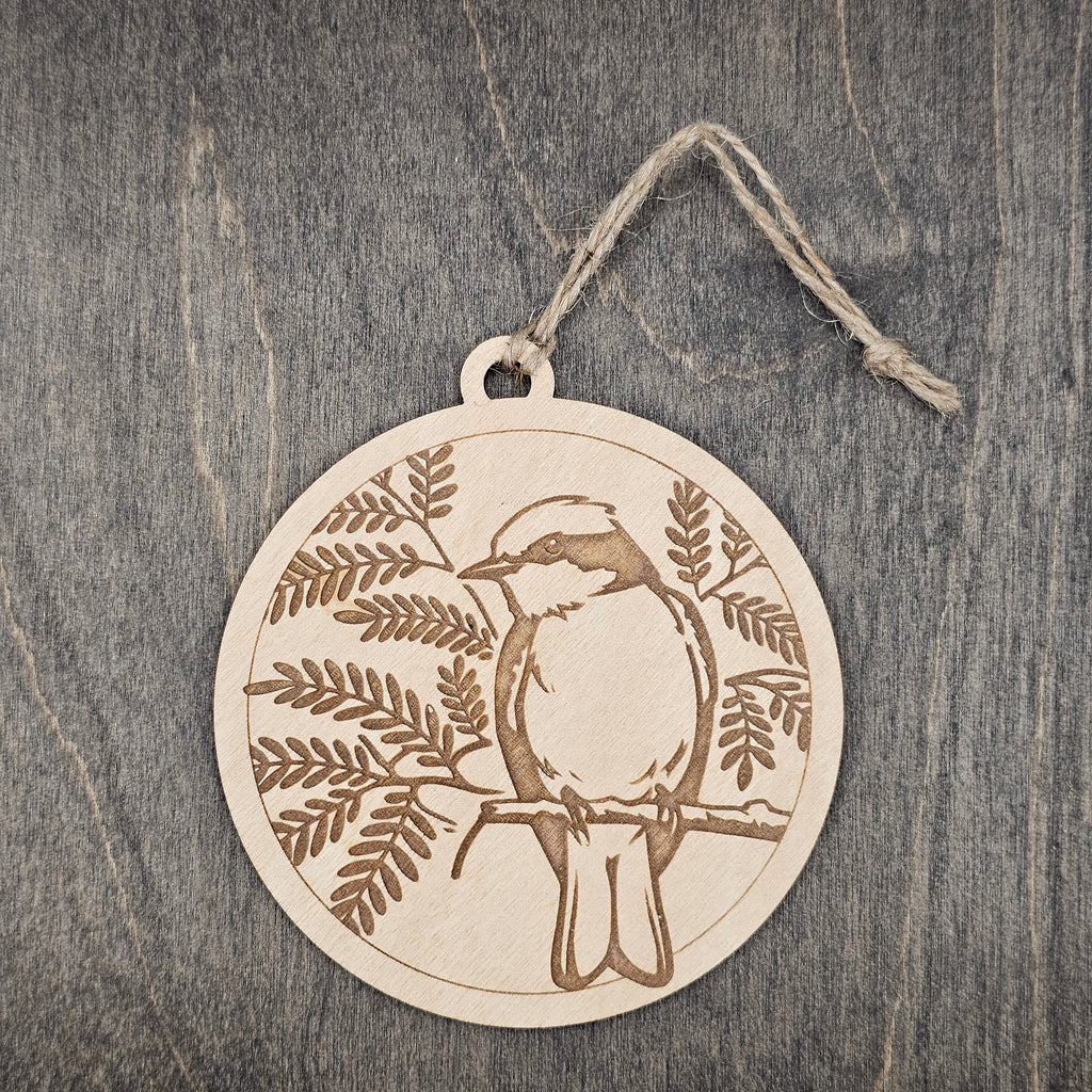 Laser engraved Vermilion Flycatcher wood ornament, featuring a detailed bird illustration surrounded by artistic fern foliage, hung with natural jute cord