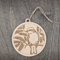 Laser engraved Vermilion Flycatcher wood ornament, featuring a detailed bird illustration surrounded by artistic fern foliage, hung with natural jute cord