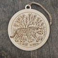 Laser engraved Ocelot wood ornament, featuring a detailed illustration of this rare South Texas wild cat walking through native brushland, hung with natural jute cord
