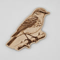 Laser-engraved wood magnet shaped like a bluebird perched on a branch with detailed feather engraving