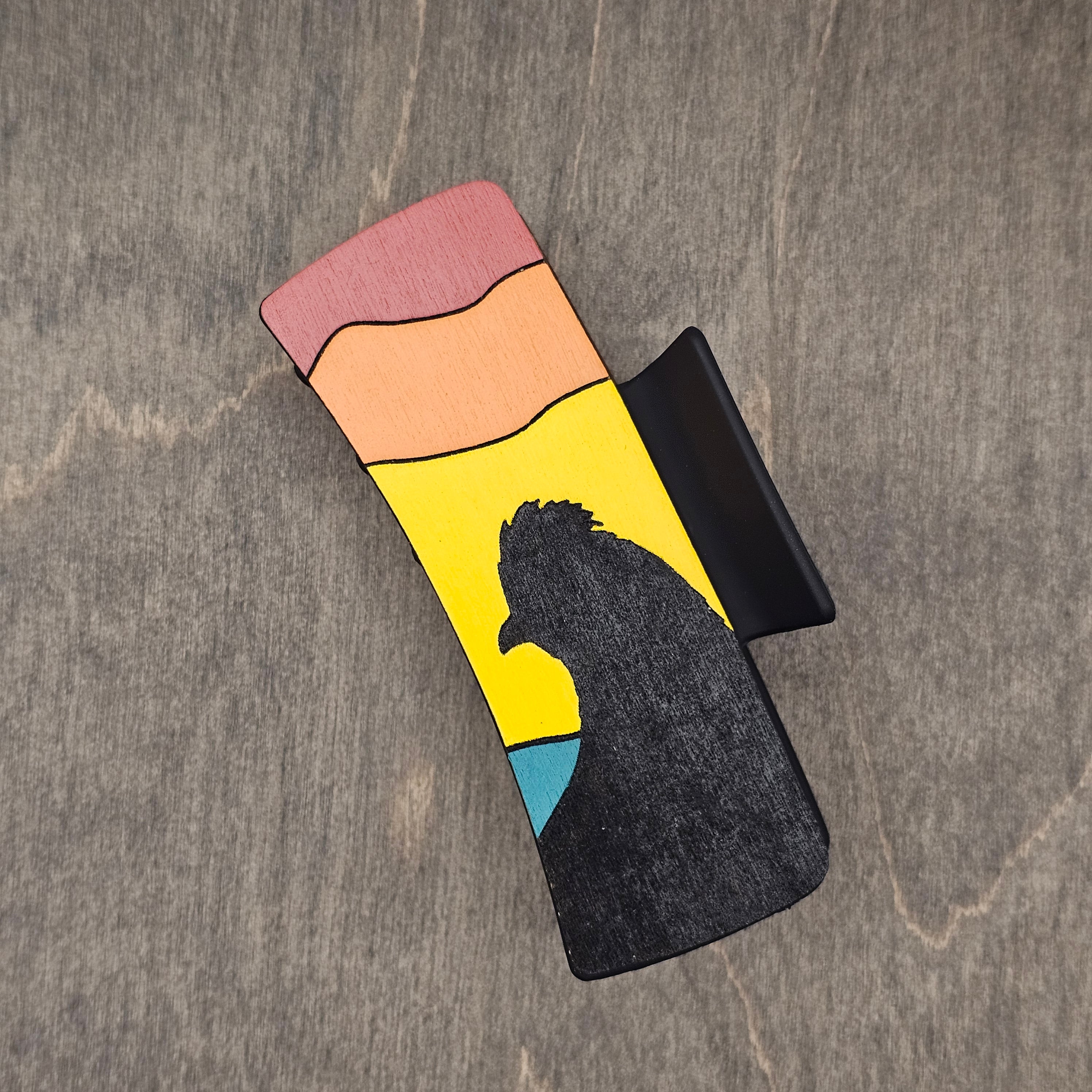 Hand-painted wood hair claw clip featuring a quail silhouette at sunset with pink, peach, yellow, and teal color bands