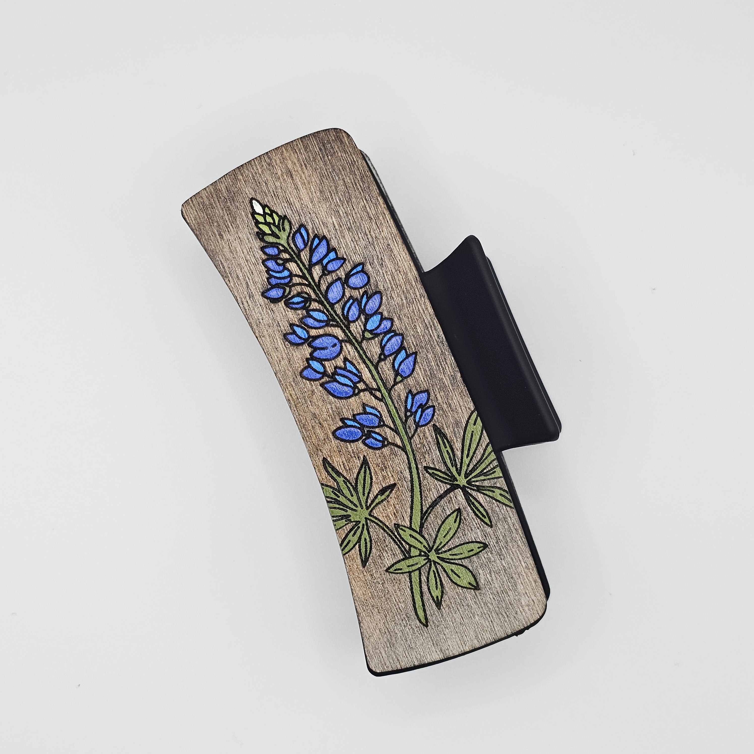 Hand-painted wood hair claw clip featuring a Texas bluebonnet with blue flowers and green leaves on a gray stained wood background