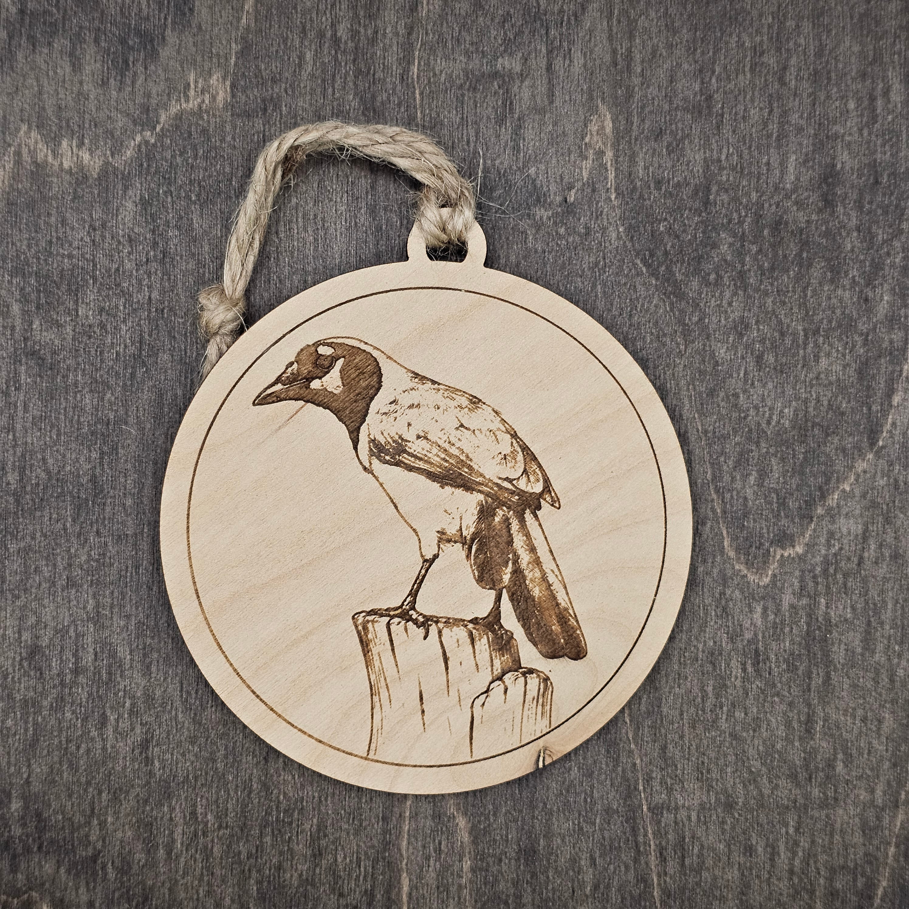 Laser engraved Green Jay wood ornament, featuring a detailed illustration of this bold South Texas bird perched on a wooden post, hung with natural jute cord