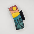 Hand-painted wood hair claw clip featuring a desert sunset scene with prickly pear cactus in teal, yellow, and red tones