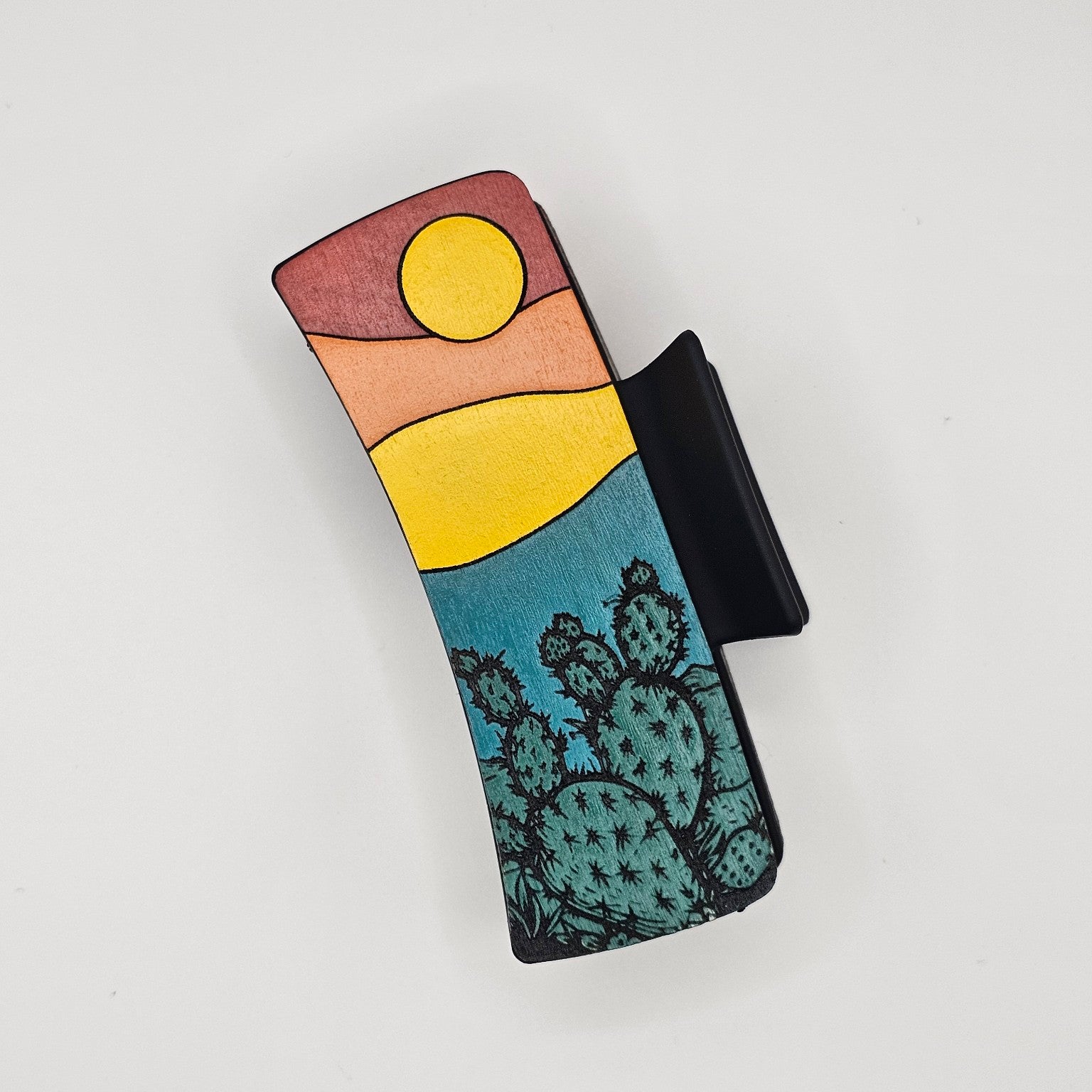 Hand-painted wood hair claw clip featuring a desert sunset scene with prickly pear cactus in teal, yellow, and red tones