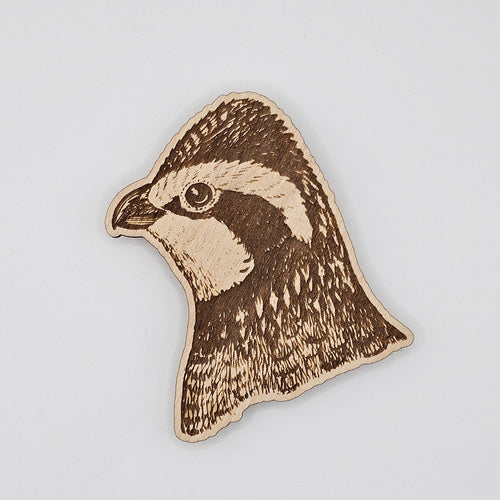 Laser-engraved wood magnet shaped like a quail head portrait with detailed feather engraving