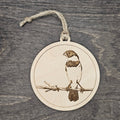 Laser engraved Morelet's Seedeater wood ornament, featuring a detailed bird illustration perched on a barbed wire fence, hung with natural jute cord