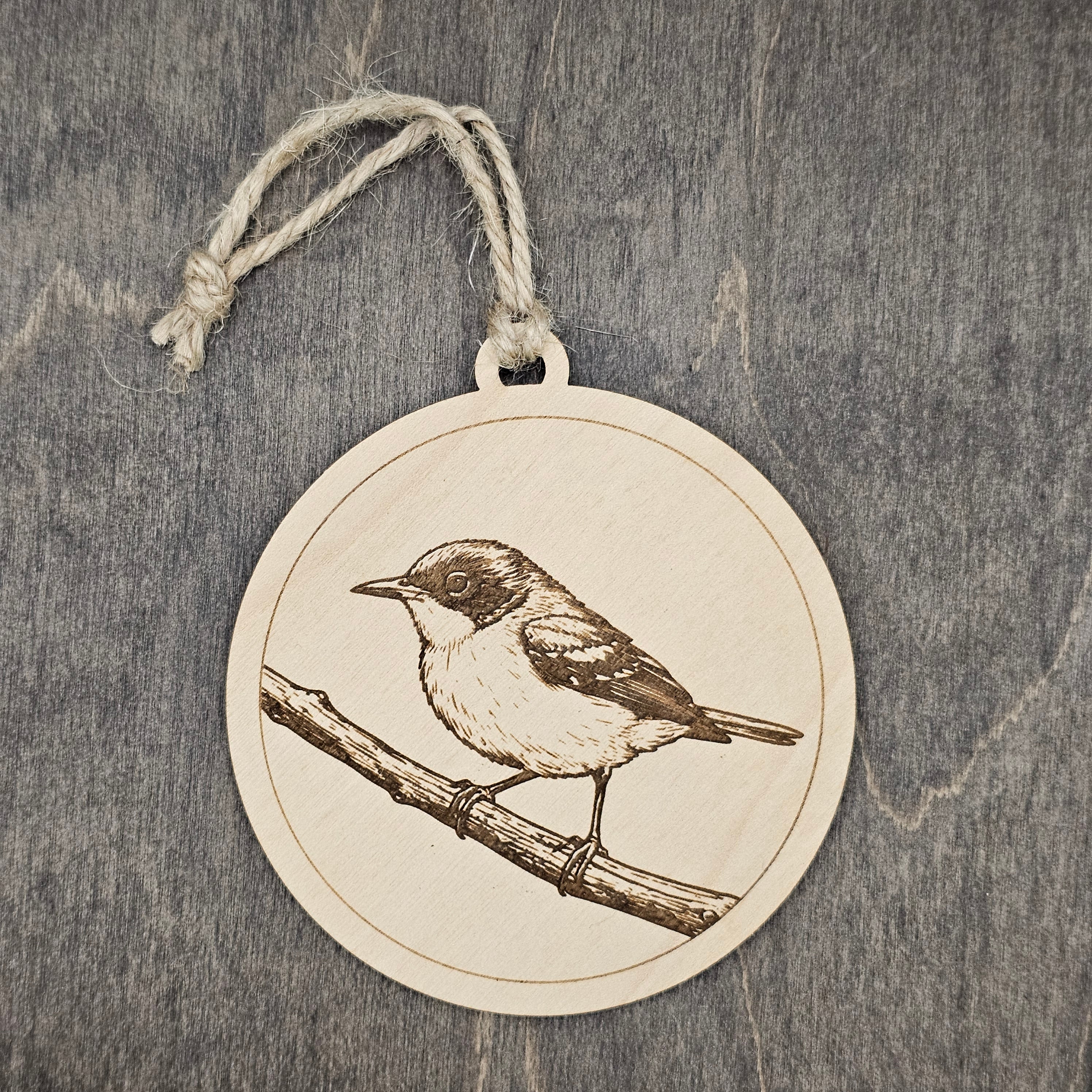 Laser engraved Hybrid Parula wood ornament, featuring a detailed bird illustration perched on a textured branch, hung with natural jute cord